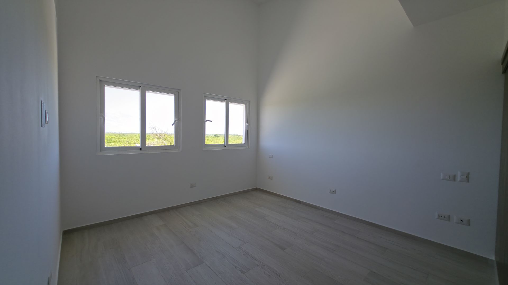 Second bedroom with windows and green views