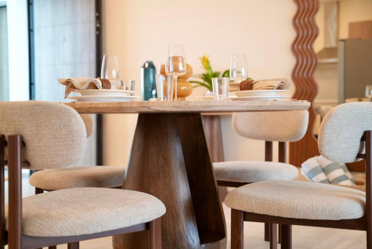 Round travertine dining table with four boucle chairs and sculpted mirror