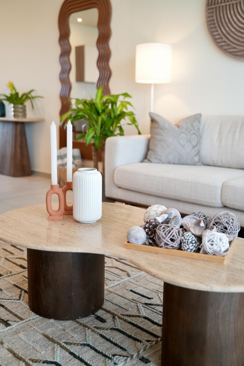 Cream sofa with travertine coffee tables, candles and sculpted mirror