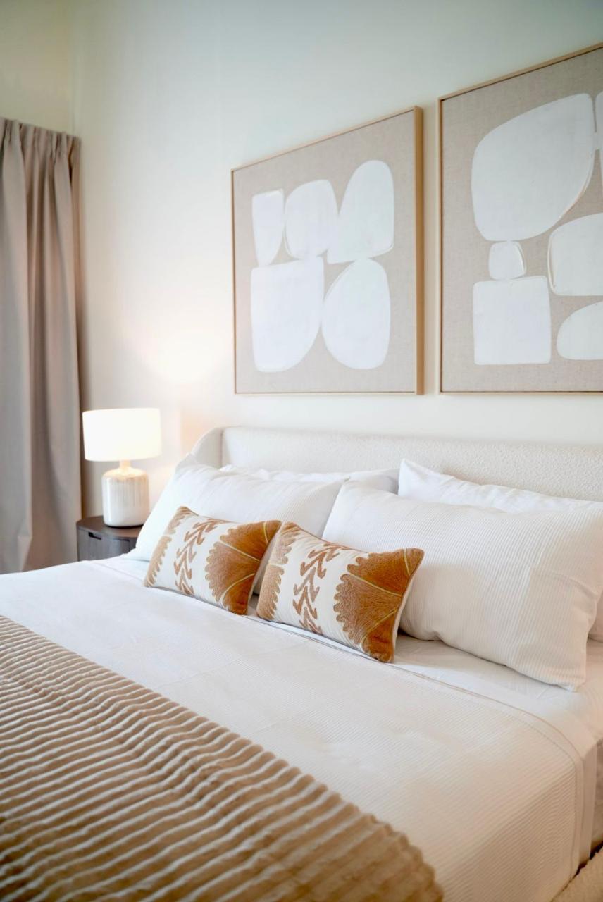 Master bedroom king bed with white linens, accent pillows and curated wall art