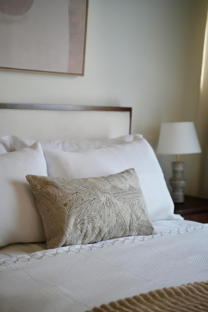 Second bedroom with upholstered headboard, designer linens and bedside lamp